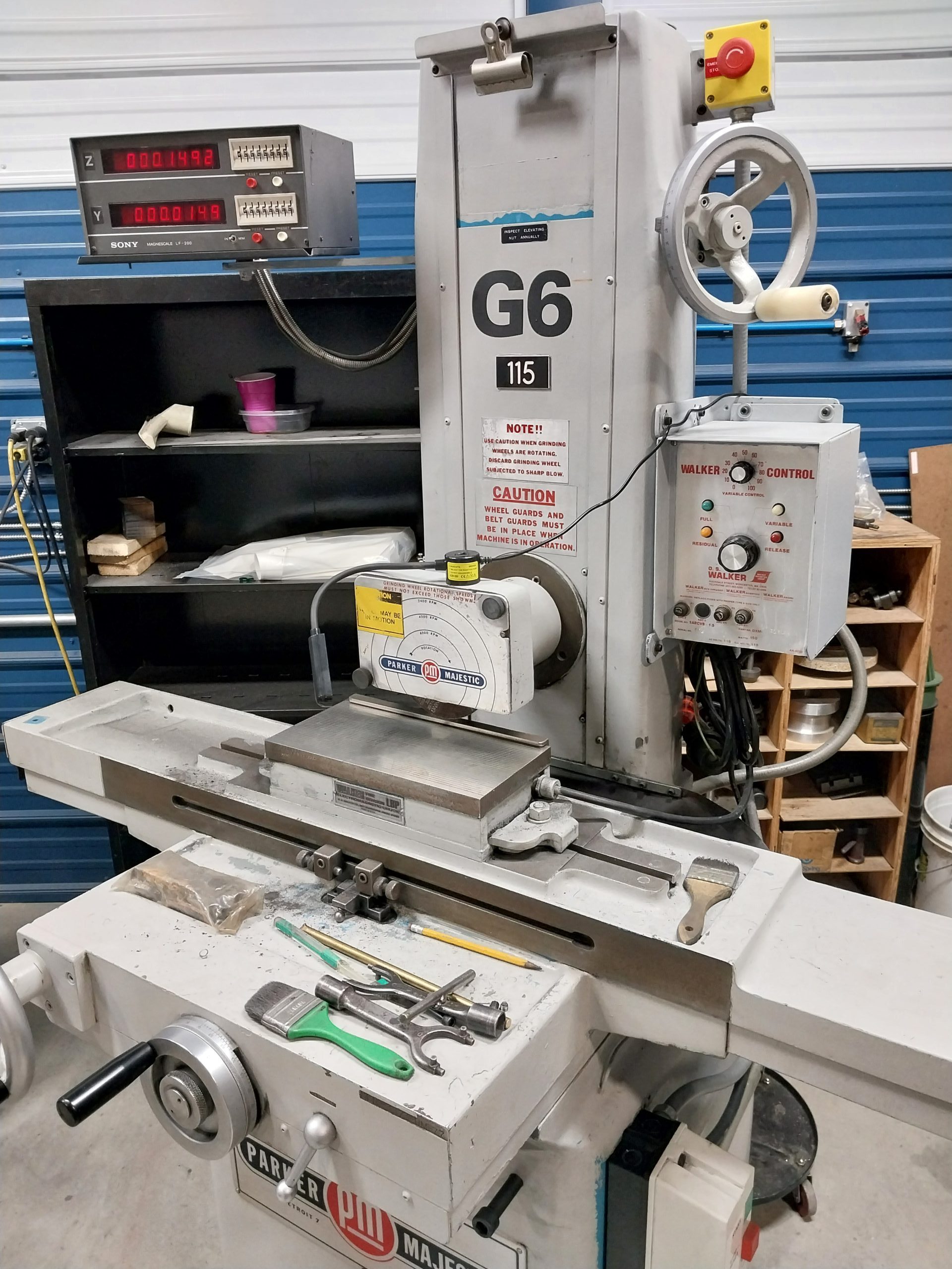 In a bustling workshop, skilled machinists operate the CNC machine labeled "G6 115," featuring control panels and adjustment knobs. A metal vise is mounted on a table with various tools, highlighting the commitment to quality. The backdrop is filled with shelves and equipment from Advanced Tooling Solutions.